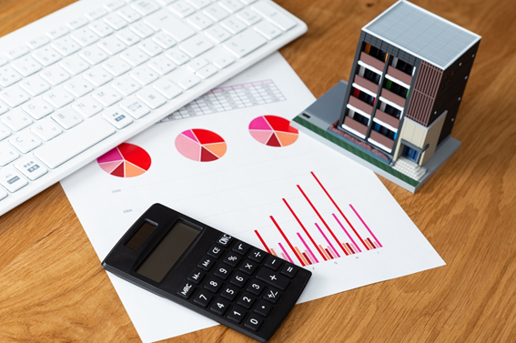 電卓と紙の資料とキーボードとマンションの模型図